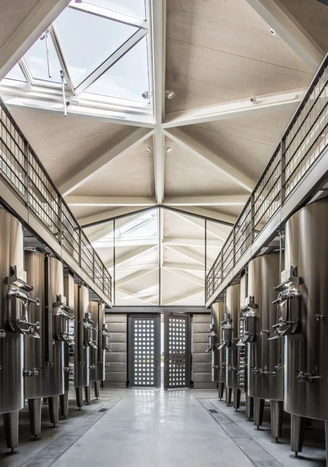 A spacious hallway with high ceilings and skylights, lined with tall, metal shelves and bright, natural light.